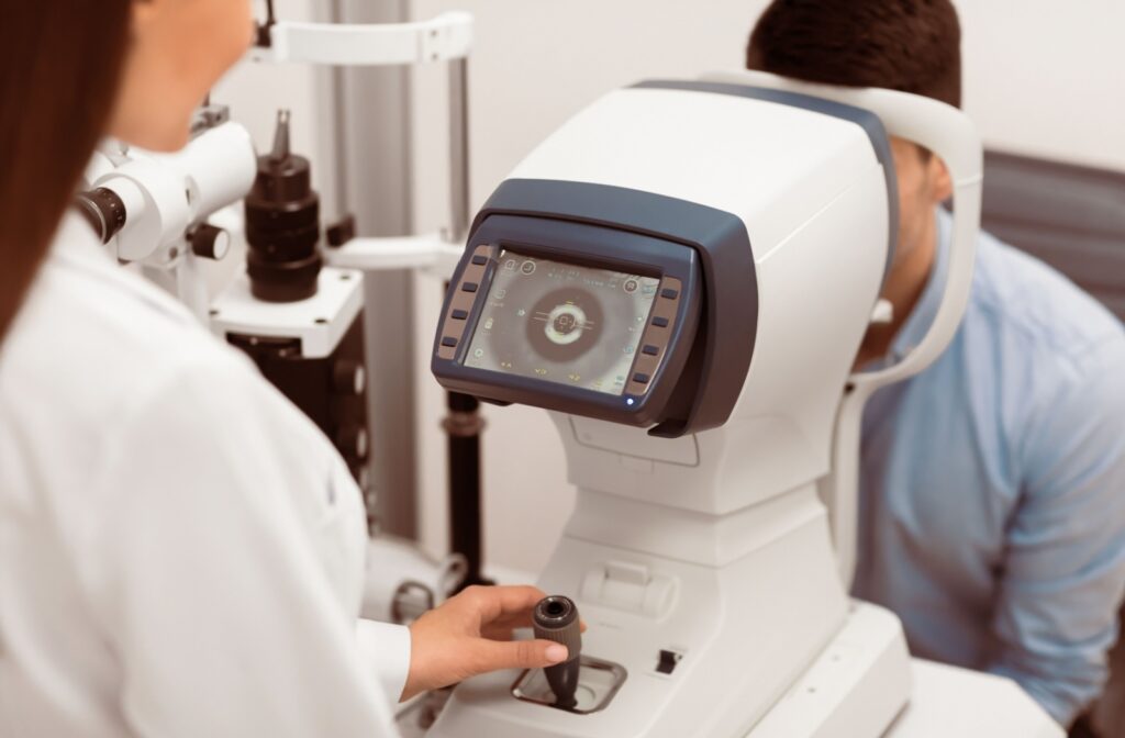 An optometrist examines their patient's eyes using a specialized camera during an eye exam.