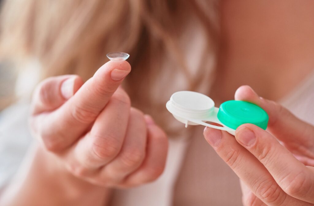 A close-up image of someone taking a contact lens out of its case.
