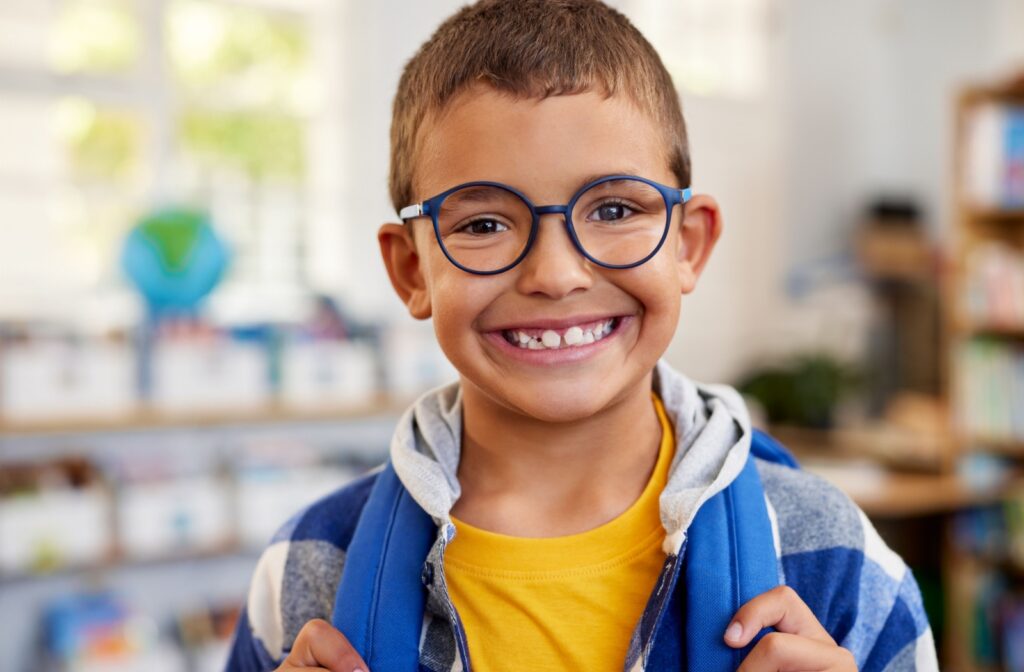 A child wearing glasses and smiling while in school