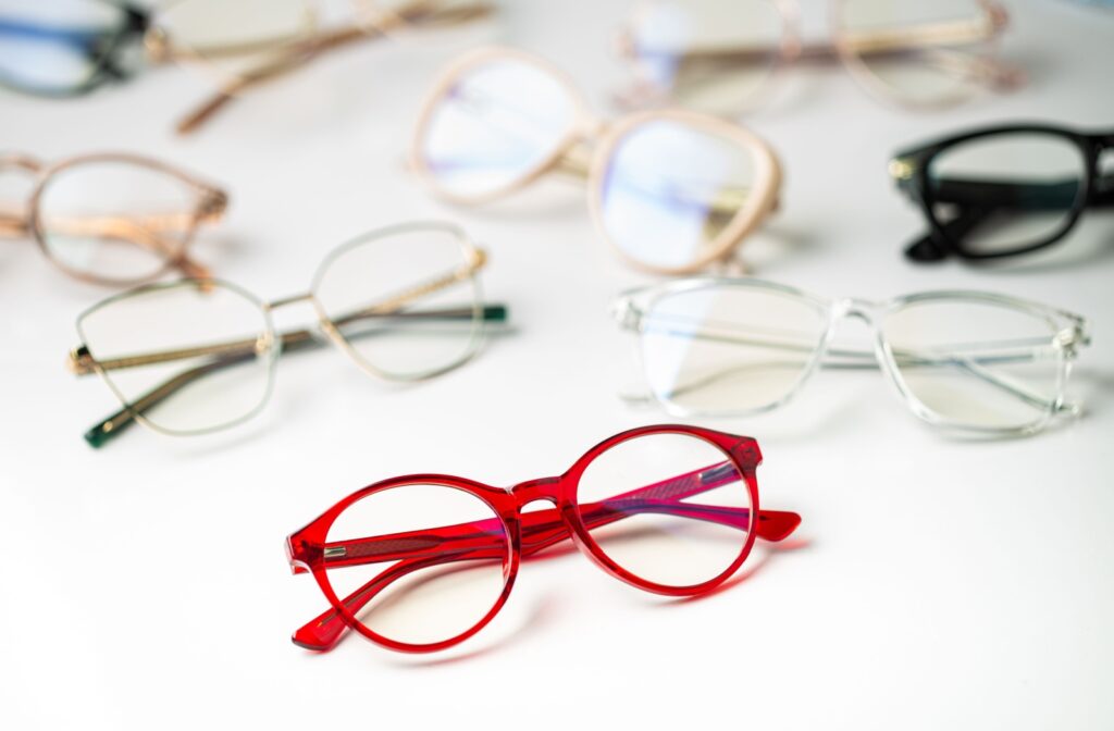 Various glasses frames sitting on a table with a pair of red glasses at the forefront