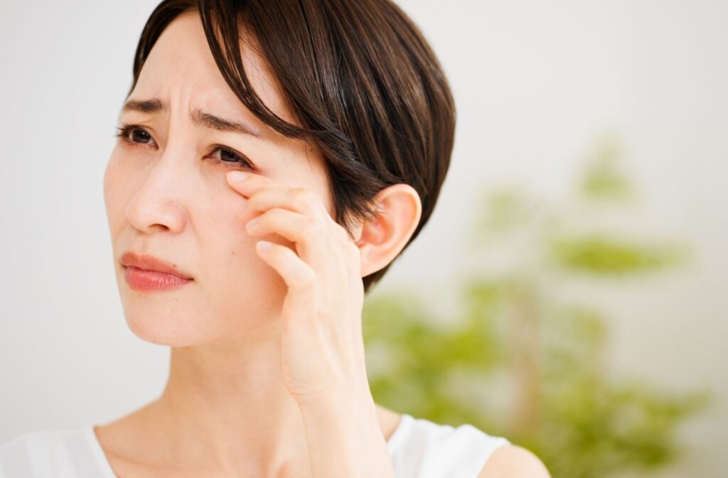 A person outside rubbing their red irritated eye caused by dry eye